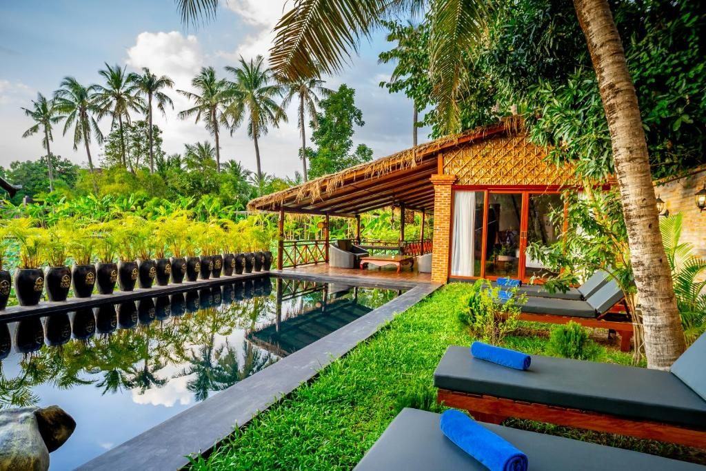Villa Coconut's private pool lined with Khmer jars, palm trees behind