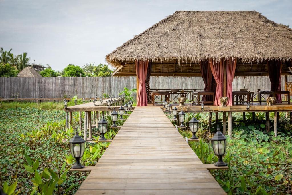 Wooden walkway to a thatched massage pavilion over the lake