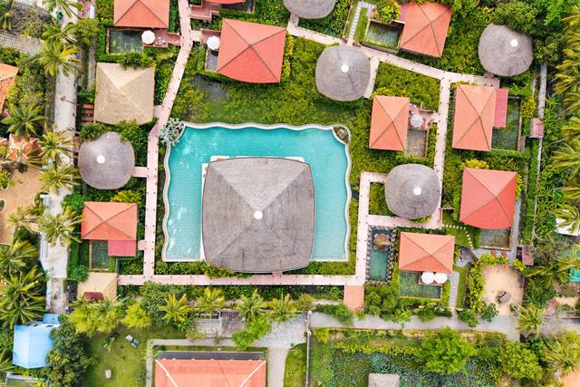 A pool villa among red-roofed bungalows, seen from above