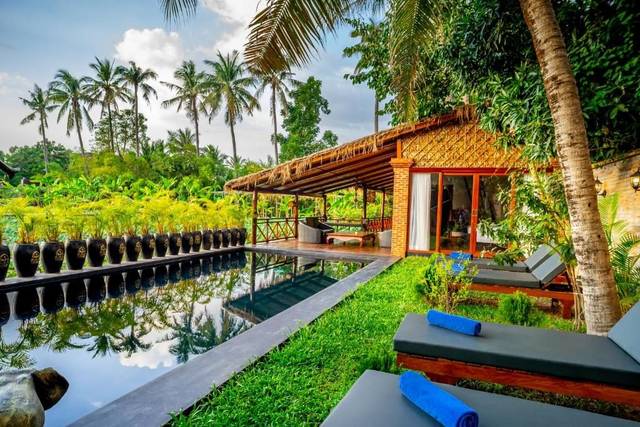 Villa Coconut's private pool lined with Khmer jars, palm trees behind