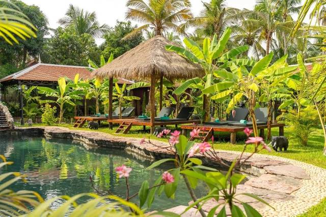The garden pool among palms and thatched salas