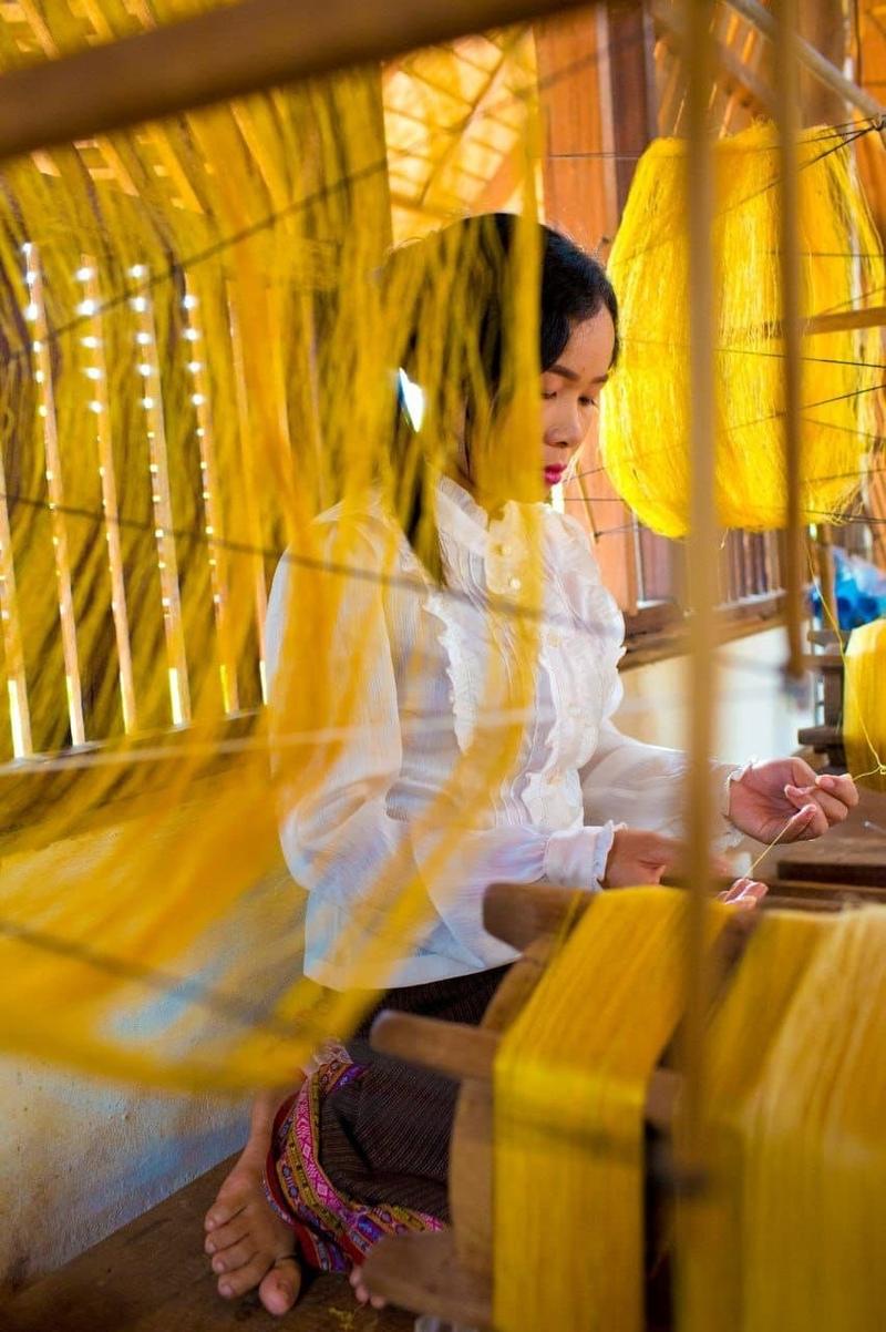Young woman spinning golden silk thread