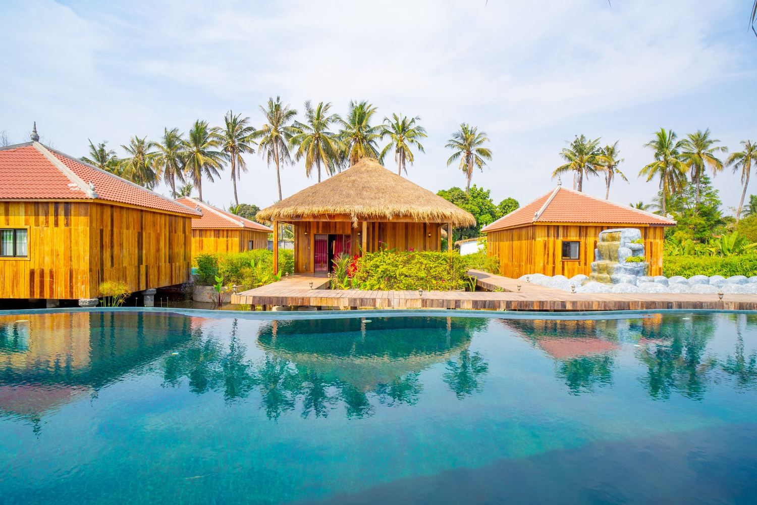 The big pool by day with wooden bungalows on its edge