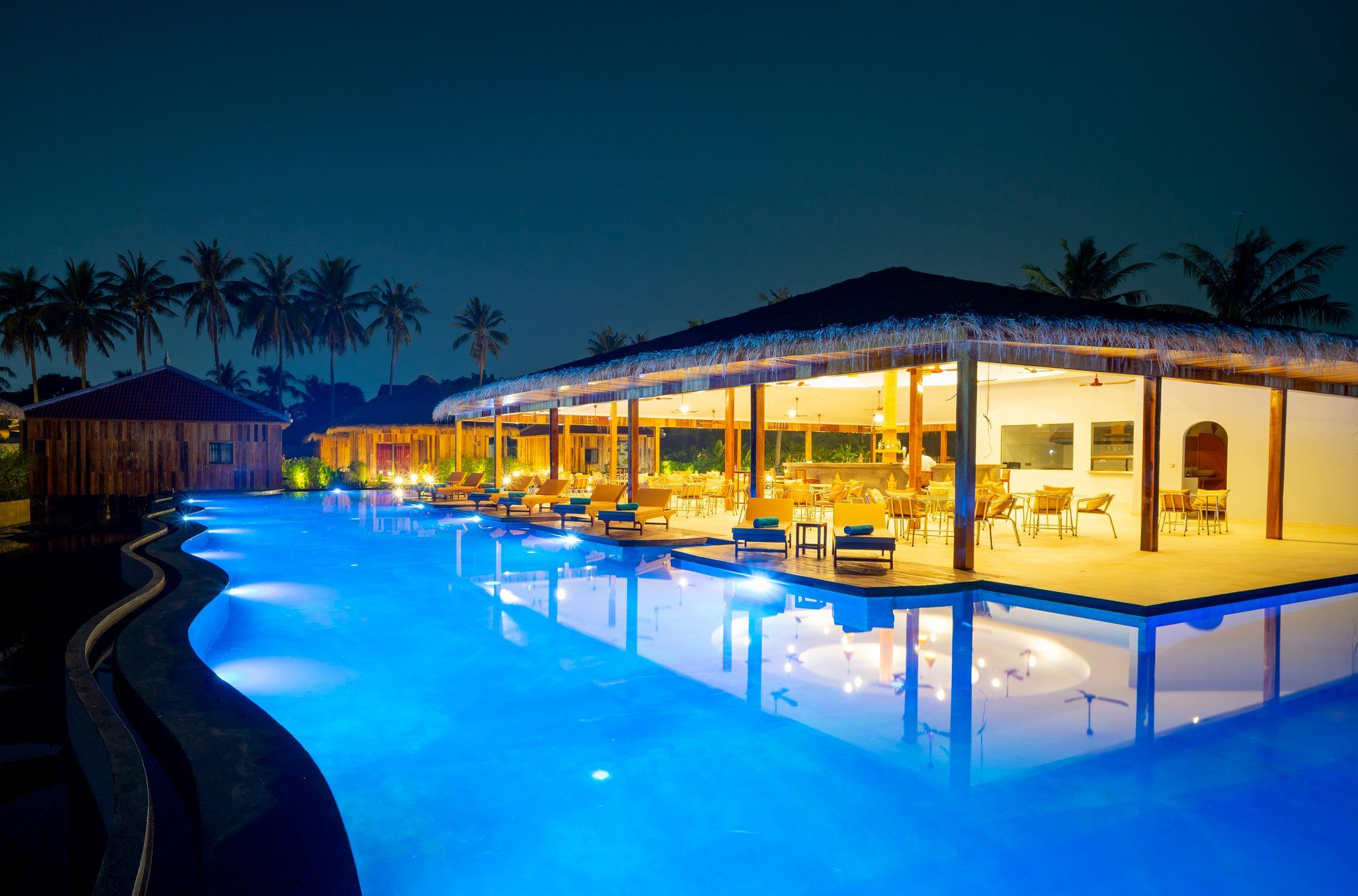 The restaurant glowing in the middle of the big pool at night